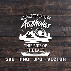 Puede incluir: Texto blanco sobre un fondo de madera que dice "Drunkest Bunch of Assholes This Side of the Lake". Una silueta blanca de una cordillera con un sol y una canoa está sobre el texto. Debajo del texto está "SVG - PNG - JPG - VECTOR".