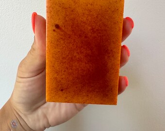 May include: A rectangular bar of orange-brown soap with a speckled texture.