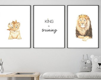 May include: Set of three framed art prints featuring lion-themed illustrations. One print shows a lion cub wearing a crown, another reads "KING in training", and the last depicts a regal lion with a crown.