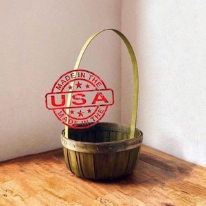 Puede incluir: Una cesta tejida verde con un asa de madera. La cesta está sentada en un suelo de madera. Un sello rojo con el texto "Made in the USA" es visible en la imagen.