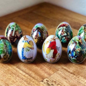 May include: Eight decorative Easter eggs with various designs featuring bunnies, flowers, and other springtime imagery. The eggs are painted in a variety of colors, including blue, green, red, and yellow.