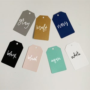 May include: Seven different color gift tags with white text. The colors are gray, kraft, navy, black, blush, aqua, and white.