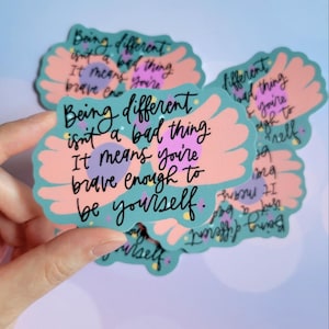 May include: A set of stickers with a teal background and pink and purple accents. The stickers feature a pair of wings and the text "Being different isn't a bad thing. It means you're brave enough to be yourself."