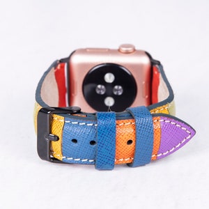 Puede incluir: Una correa de reloj de cuero colorida con una hebilla negra. La correa est&aacute; hecha de m&uacute;ltiples rayas de cuero amarillo, naranja, azul y morado.