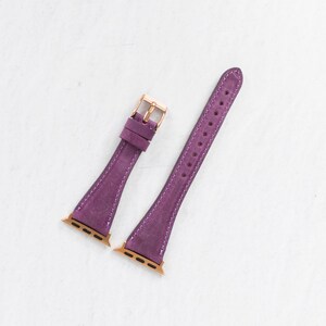 May include: Two purple leather watch bands with gold hardware. The bands are designed for Apple Watches.