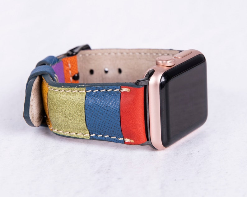 Puede incluir: Una correa de reloj de cuero colorida con rayas verdes, azules, rojas y moradas. La correa est&aacute; unida a un Apple Watch de oro rosa.