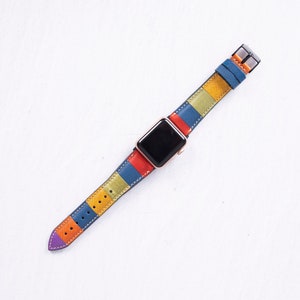 Puede incluir: Una correa de reloj a rayas de colores con una esfera negra. La correa est&aacute; hecha de cuero y tiene una variedad de colores, incluyendo rojo, naranja, amarillo, azul y verde.