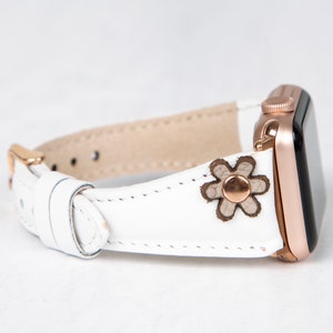 Pode incluir: Pulseira de rel&oacute;gio Apple de couro branco com fivela de ouro rosa e um pequeno design floral.