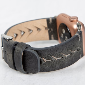 May include: A black leather watch strap with white stitching and a rose gold Apple Watch.