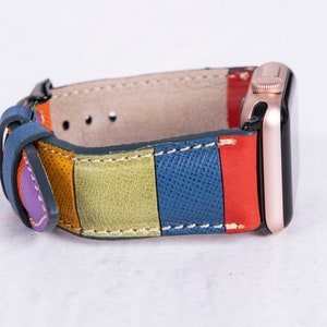 Puede incluir: Una correa de reloj de cuero colorida con rayas de morado, naranja, verde, azul y rojo. La correa est&aacute; unida a un Apple Watch de oro rosa.
