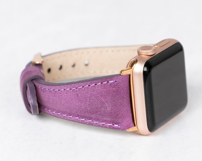 May include: A purple leather watch band with a rose gold Apple Watch.