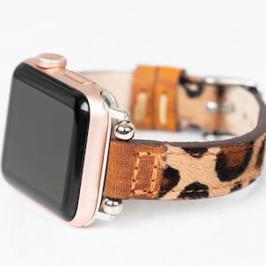 May include: A rose gold Apple Watch with a brown leather band featuring a leopard print design.
