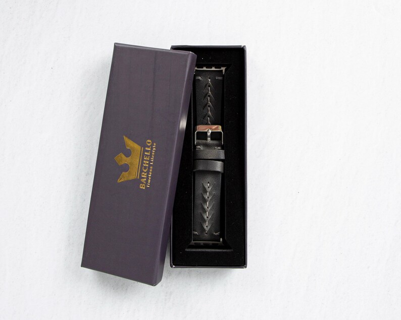 The watch band and rose gold watch case displayed inside an open dark purple gift box with gold logo lettering.