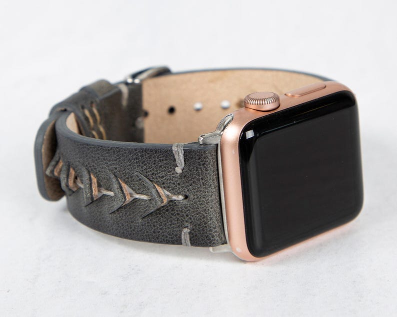 An angled view of the gray leather watch band attached to a rose gold Apple Watch with a black screen.