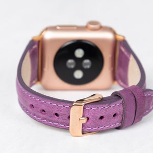 May include: A purple leather watch band with a rose gold buckle and a rose gold Apple Watch face.