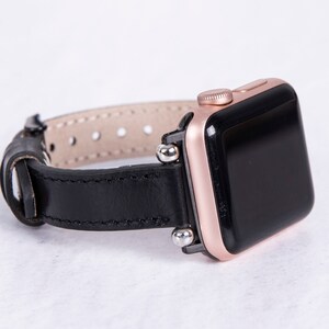 Puede incluir: Una correa de reloj de cuero negro con detalles en oro rosa y una esfera negra. La correa tiene un cierre de hebilla y est&aacute; dise&ntilde;ada para un reloj inteligente.