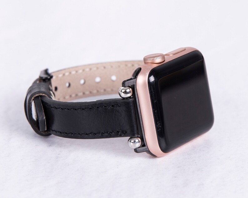 Puede incluir: Una correa de reloj de cuero negro con detalles en oro rosa y una esfera negra. La correa tiene un cierre de hebilla y est&aacute; dise&ntilde;ada para un reloj inteligente.
