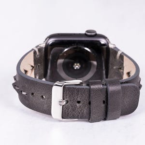 A rear-view close-up focusing on the silver metal buckle and loops of the gray leather watch band.