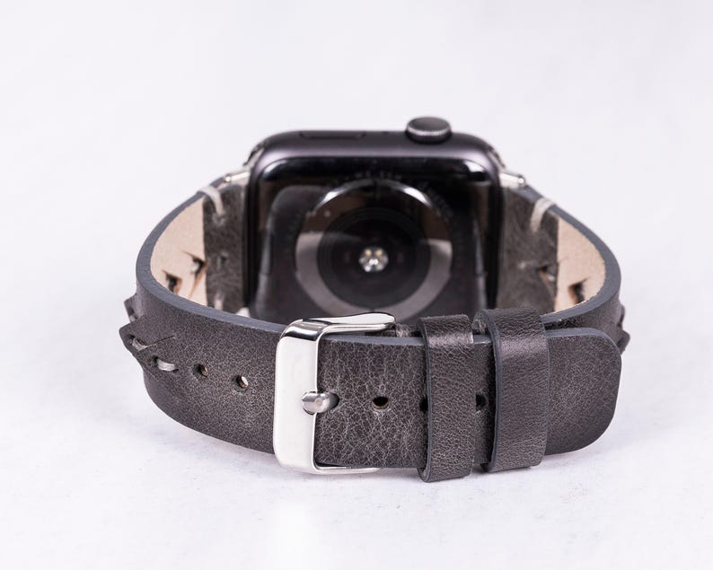 A rear-view close-up focusing on the silver metal buckle and loops of the gray leather watch band.
