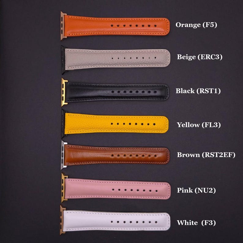 K&ouml;nnte beinhalten: Eine Auswahl an Leder-Armb&auml;ndern in verschiedenen Farben, darunter Orange, Beige, Schwarz, Gelb, Braun, Rosa und Wei&szlig;. Jedes Band hat eine Reihe von L&ouml;chern zur Anpassung und ist mit einem Code versehen.
