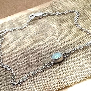 May include: A silver chain bracelet with a single oval-shaped opal gemstone.