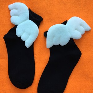 May include: A pair of black socks with white angel wings on the top of each sock.