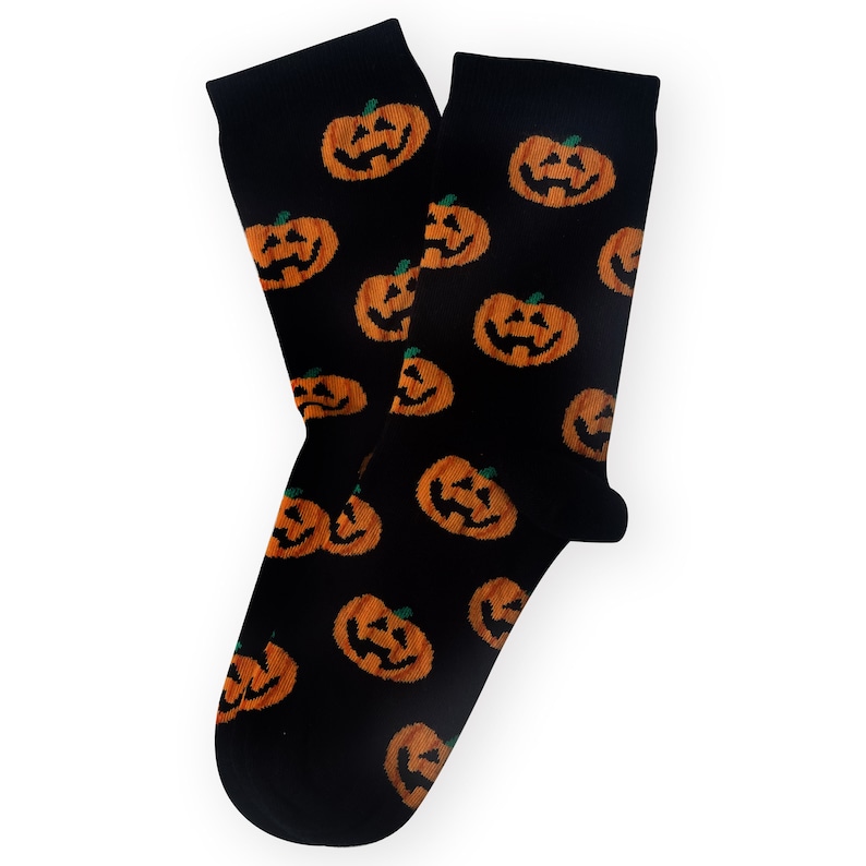 May include: Black socks with an all-over pattern of orange jack-o'-lanterns. The socks are made of a soft material and are perfect for Halloween. The pumpkins have carved faces and green stems.