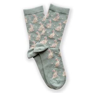 Peut inclure: Une paire de chaussettes bleu clair avec un motif de lapin blanc. Les chaussettes sont pli&eacute;es ensemble et les orteils pointent vers le bas de l'image.