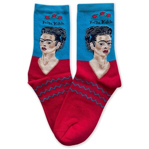 May include: A pair of red and blue socks with a portrait of Frida Kahlo and the text "Frida Kahlo" on each sock.