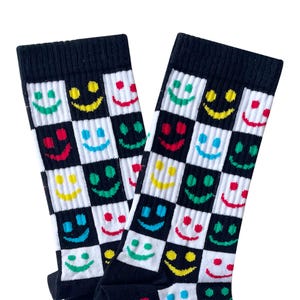 May include: A pair of black and white checkered socks with colorful smiley faces. The socks have a red, yellow, green, and blue smiley face pattern.