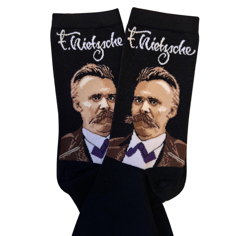 May include: A pair of black socks with a portrait of Friedrich Nietzsche on each sock. The socks have the text "F. Nietzsche" written in white on the top of each sock.
