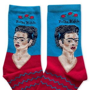 May include: A pair of blue and red socks with a portrait of Frida Kahlo and the text "Frida Kahlo" on the top of each sock.
