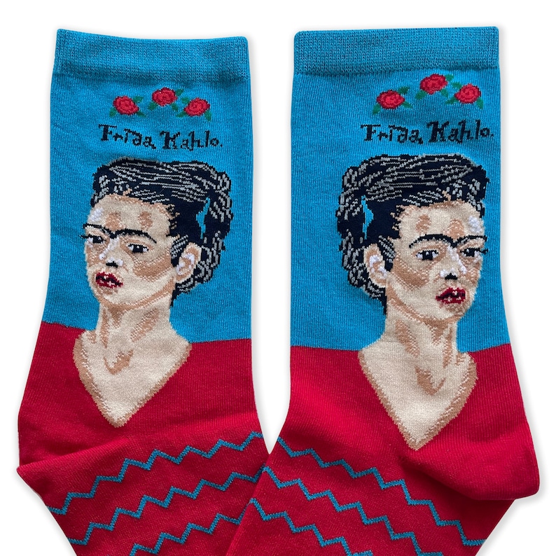 May include: A pair of blue and red socks with a portrait of Frida Kahlo and the text "Frida Kahlo" on the top of each sock.