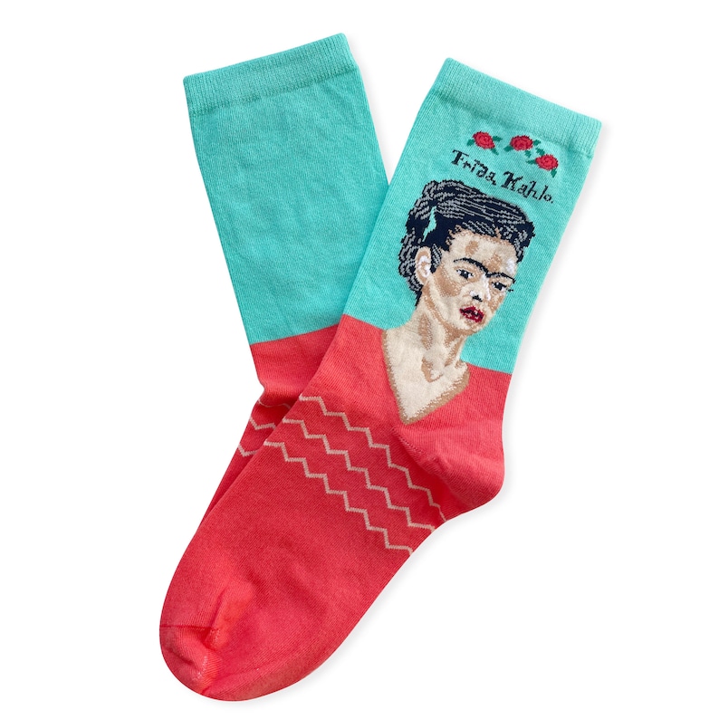 May include: A pair of turquoise and coral socks with a portrait of Frida Kahlo and the text "Frida Kahlo" in black.