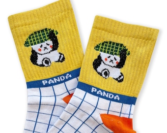 Op de afbeelding: Een paar gele sokken met een wit en blauw geruit patroon. Elke sok heeft een panda die een groene geruite hoed draagt. De sokken hebben het woord "PANDA" op de blauwe band.