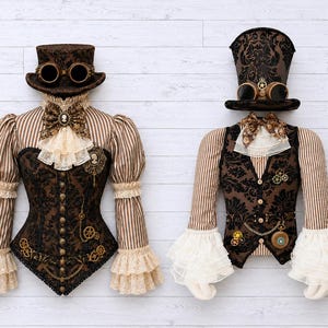 May include: Two outfits featuring brown and cream striped long-sleeve shirts with ruffled cuffs, brown damask corsets and vests, lace jabots with cameo pins, and top hats adorned with brass-colored goggles and mechanical gear embellishments.