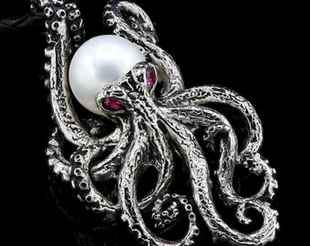 May include: A silver octopus pendant with a large white pearl held in its tentacles. The octopus has textured details and two small red gemstones. The pendant hangs from a black cord, set against a black background.