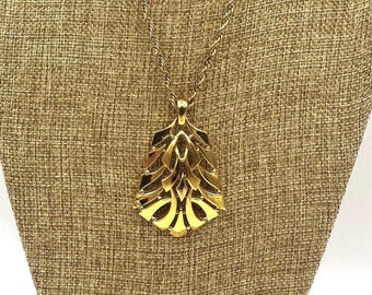Collana con pendente modernista Trifari, color oro, traforata, con design a onda, anni '70, firmata.