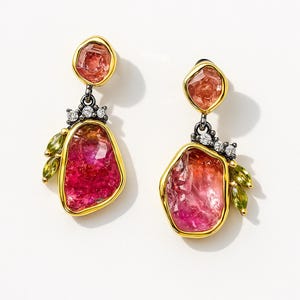 May include: A pair of dangle earrings featuring large, irregular-shaped pink and orange gemstones set in gold-colored bezels. The earrings have a small cluster of white gemstones and green leaf-shaped accents.