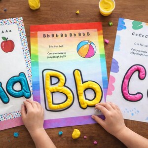 May include: Educational activity sheets with the letters A, B, and C. Each sheet features a large letter made of playdough, with illustrations of an apple, ball, and cat. The sheets are designed for children's learning.