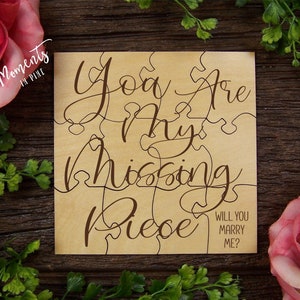 May include: Wooden puzzle piece with the text "You are my missing piece" and "Will you marry me?" in brown cursive font on a light brown background.