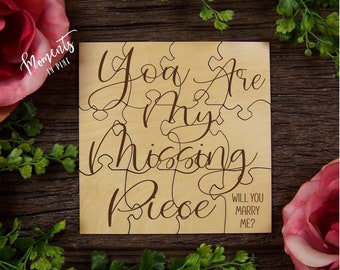 May include: Wooden puzzle piece with the text "You are my missing piece" and "Will you marry me?" in brown cursive font on a light brown background.