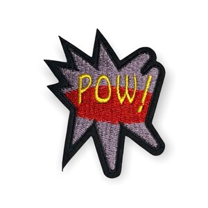 Può includere: Una toppa in stile fumetto a forma di stella. La toppa presenta la parola "POW!" in giallo, su uno sfondo rosso e grigio, con un bordo nero. La toppa è probabilmente per abbigliamento o accessori.