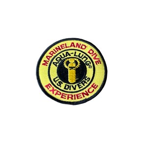May include: A round, embroidered patch with a yellow background and black and red text. The text reads "Marineland Dive", "Aqua-Lung", "US Divers Experience". A gold and black diving figure is in the center.