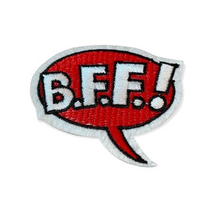 Może przedstawiać: Czerwona, biała i czarna naszywka w kształcie dymka. Zawiera białe litery "B.F.F.!" na czerwonym tle z białym obramowaniem. Przeznaczona do naszywania na odzież lub akcesoria.