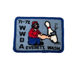 May include: Embroidered patch with a light blue background and a dark blue border. The patch features a cartoon of a bearded man in a red shirt and blue pants, holding a bowling pin. Text includes "71-72", "WWBA", and "EVERETT, WASH."