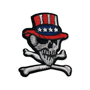 Puede incluir: Parche bordado con una calavera que lleva un sombrero rojo, blanco y azul del Tío Sam. La calavera tiene huesos cruzados debajo. El parche es blanco, negro, rojo y azul.