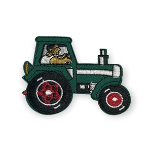 Könnte beinhalten: Gestickter Aufnäher eines grünen Traktors mit schwarzen Rädern und roten Akzenten. Der Traktor hat einen Fahrer in der Kabine. Zum Aufnähen auf Kleidung oder Accessoires.