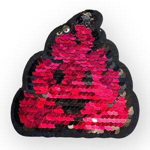 May include: A sequined patch in the shape of a pile of poop. The sequins are primarily red with some black and silver accents. The patch is outlined with a black felt material.