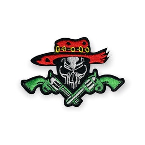 May include: Embroidered patch featuring a skull wearing a red cowboy hat with gold accents. Two green revolvers are crossed below the skull. The patch has a black border and is designed for application on clothing or accessories.
